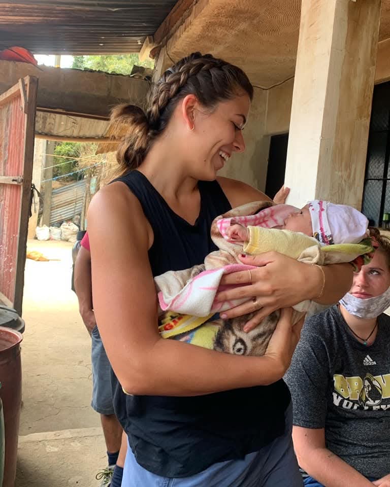 A volunteer holding a newborn in a rural home